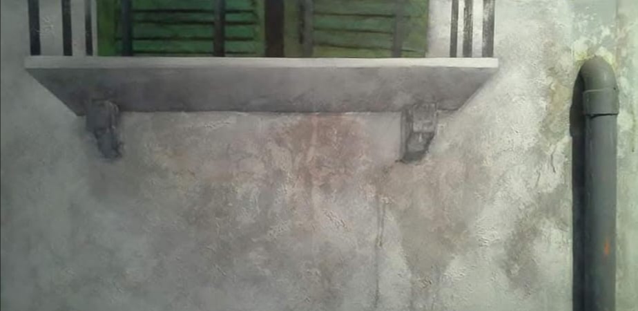 Muro grigio con balcone e persiane verdi in primo piano